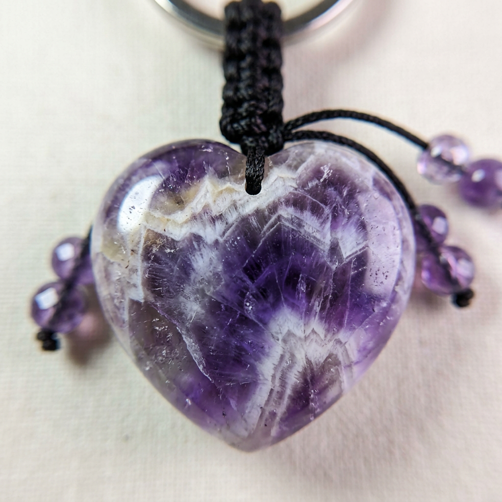 Macro close-up detail of polished chevron amethyst heart and purple beads